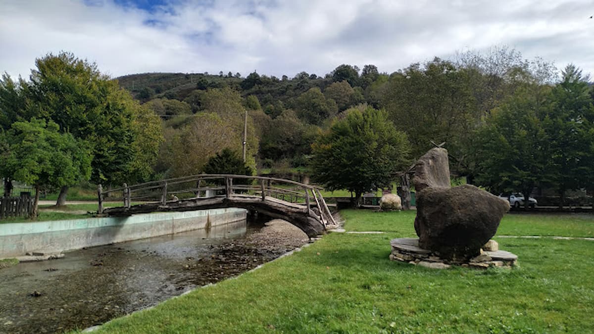 Puente de madera rústico sobre el río en Balboa, rodeado de árboles y montañas.