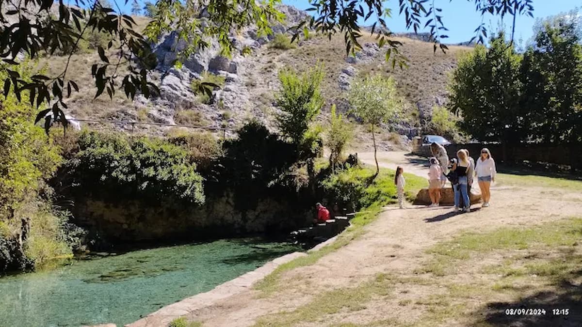 Piscina natural de la Fuente de la Salud en Sepúlveda, rodeada de vegetación y montañas.