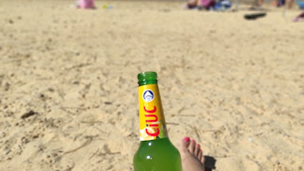 Persona descansando en la arena de Playa Pita con una bebida en la mano y vistas al pantano.