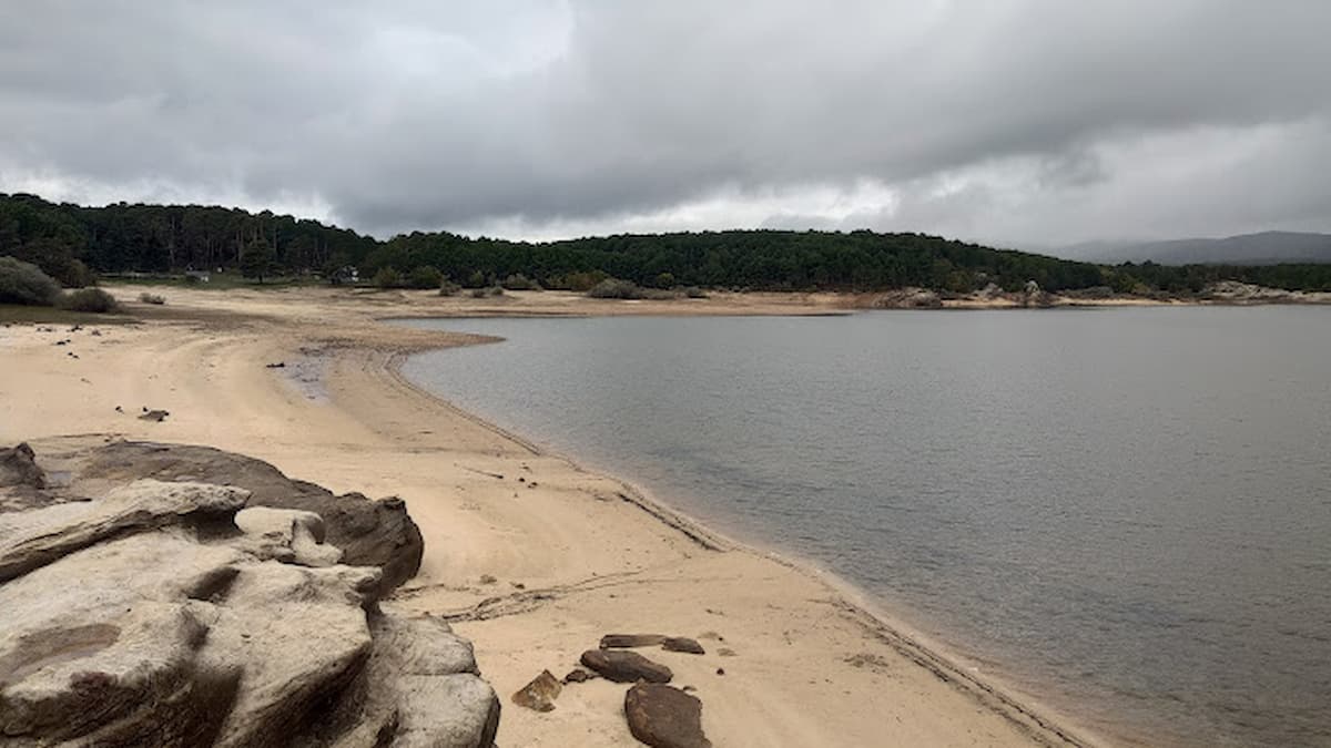 Vista panorámica de la playa con arena dorada y el pantano bajo un cielo nublado.
