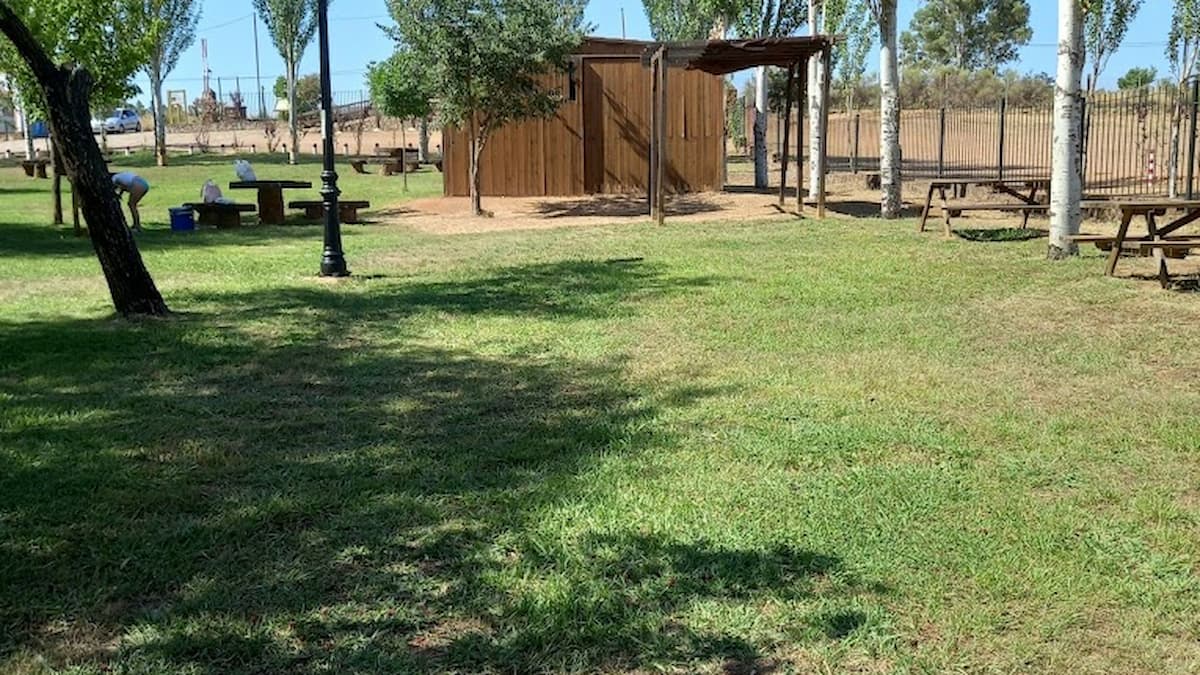 Zona de picnic con mesas de piedra en La Codosera, rodeada de césped y árboles.