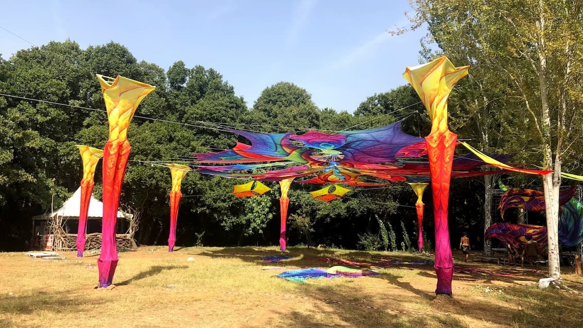 Festival con decoraciones psicodélicas de colores vibrantes en un área verde de La Codosera.