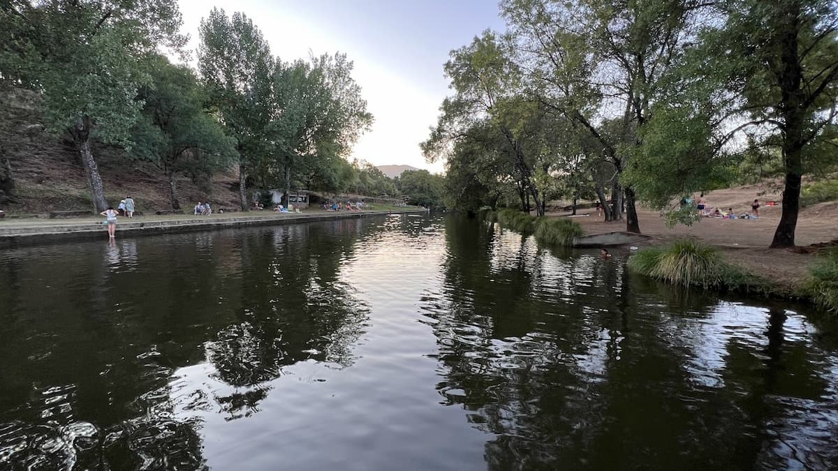 Piscina natural rodeada de árboles con reflejos en el agua.