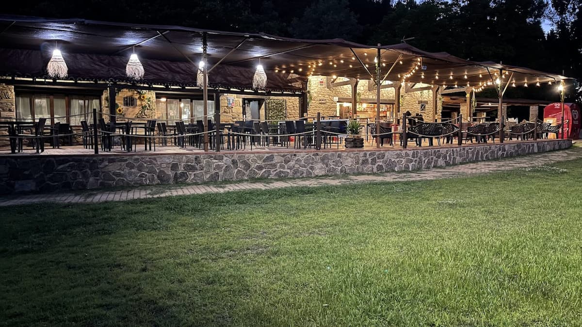 Terraza iluminada de un merendero junto a la piscina natural.